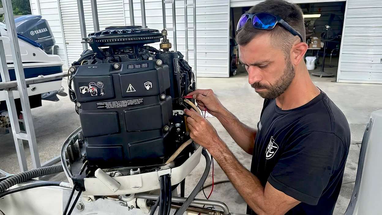 Marine service technician repairing an outboard motor at Pinellas Park boat dealership